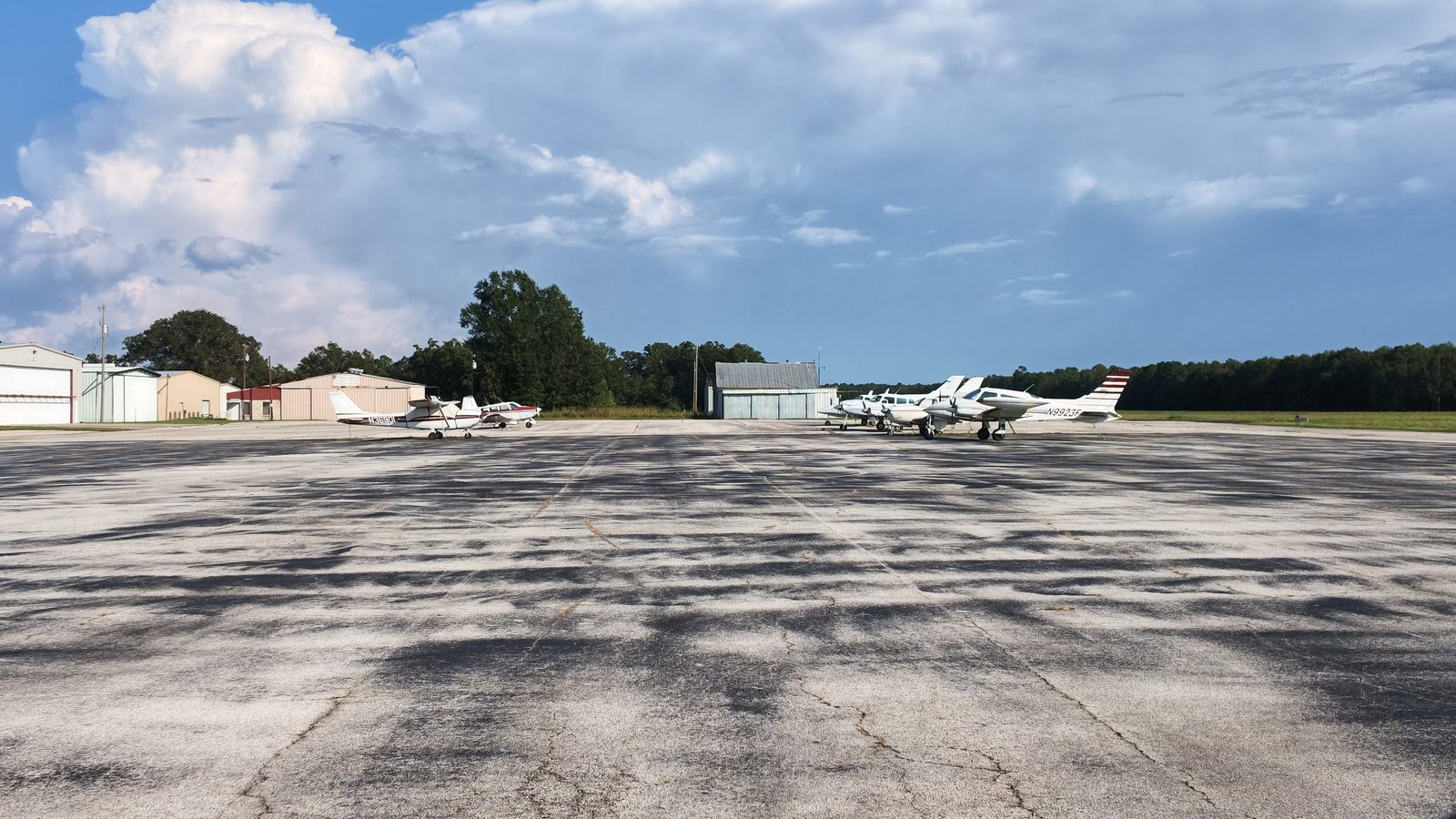 Light aircraft parked on the apron at Livingston Municipal Airport with hangars behind.