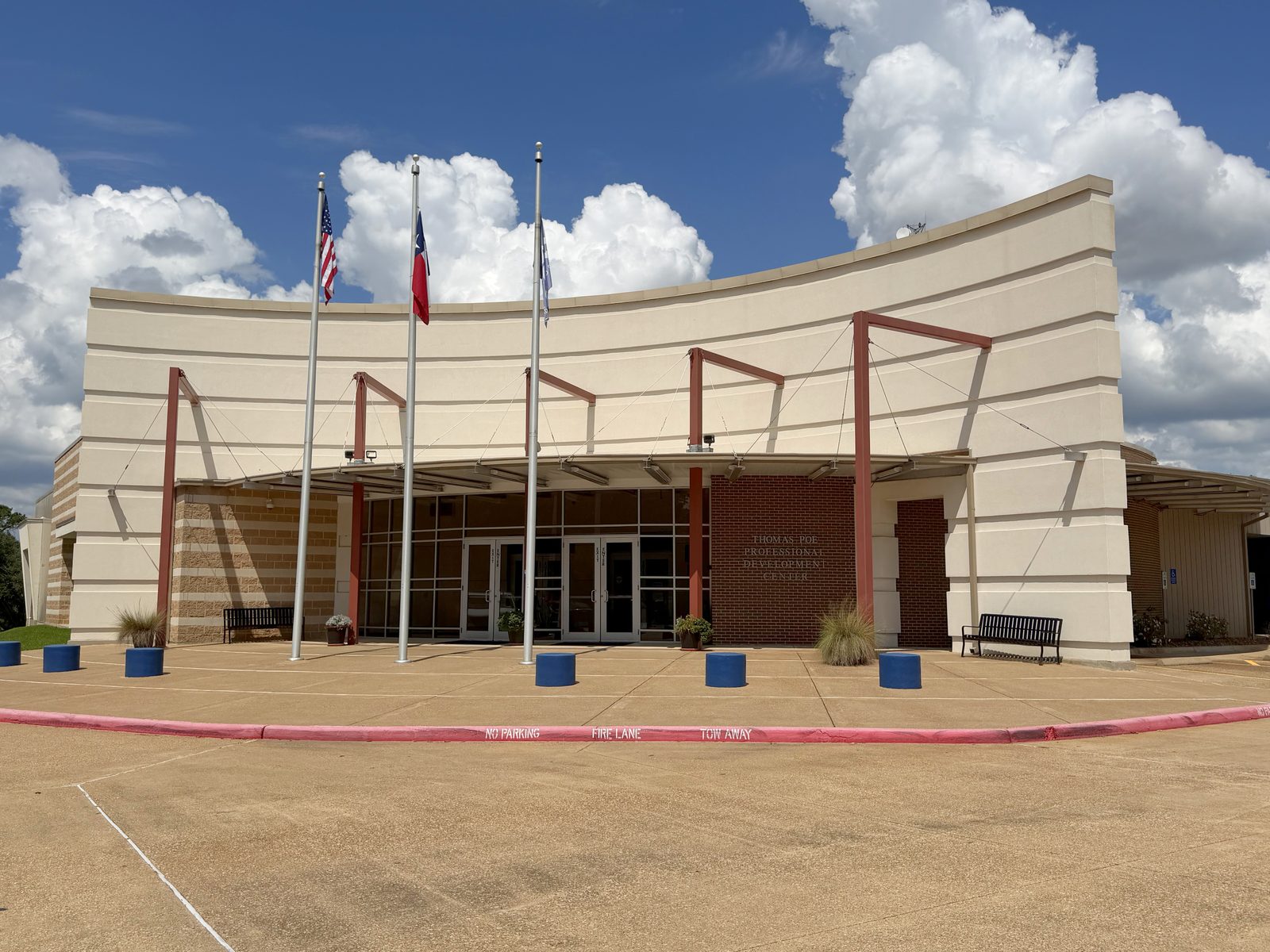 The Region 6 Education Service Center: a long curved cream-colored building with a covered entrance, and United States, Texas and Region 6 flags flying on poles outside.